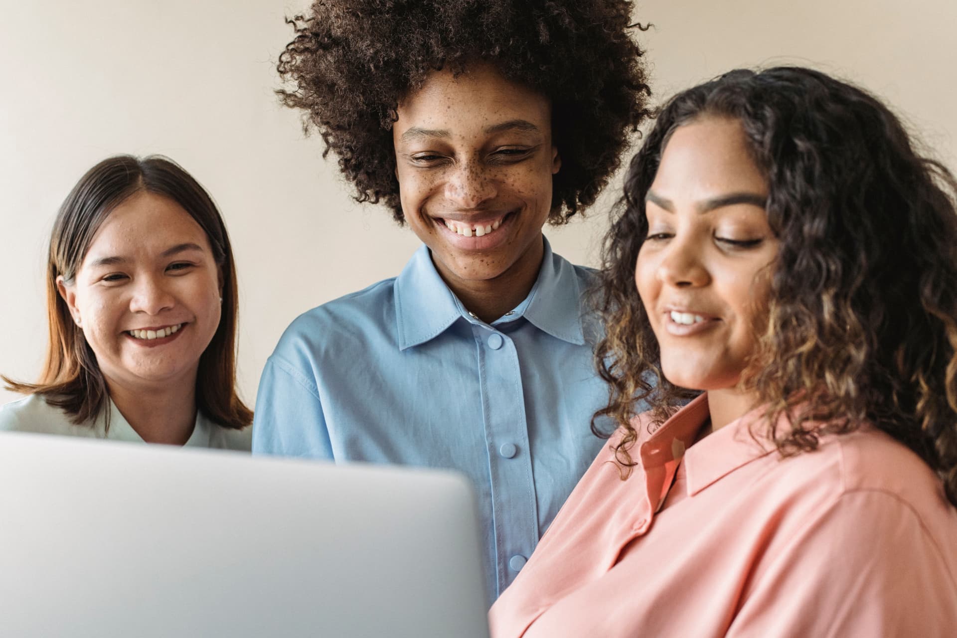 Three women smiling while looking at a laptop together